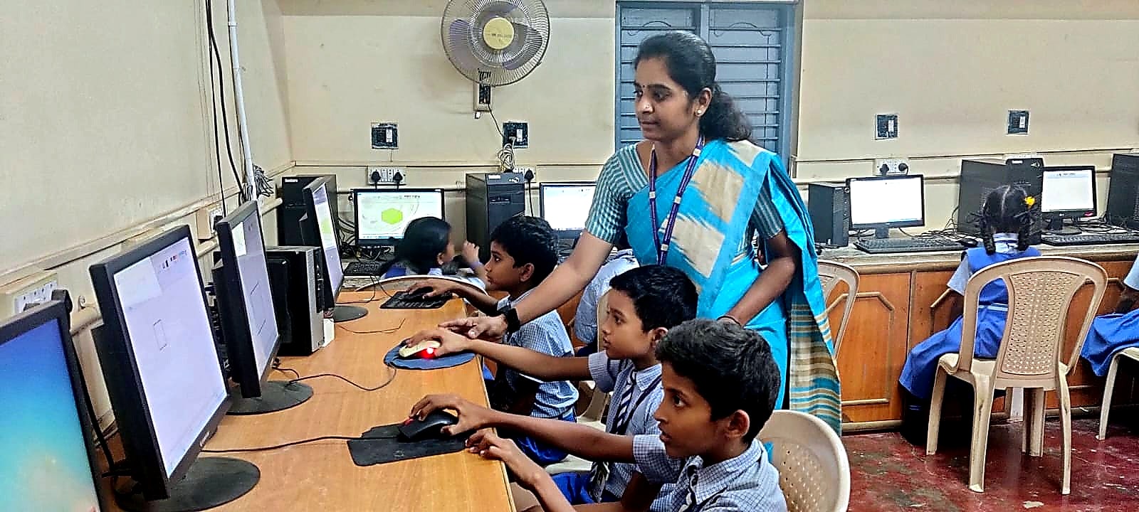Manjushree students at computers in the school's computer room, with the teacher supervising