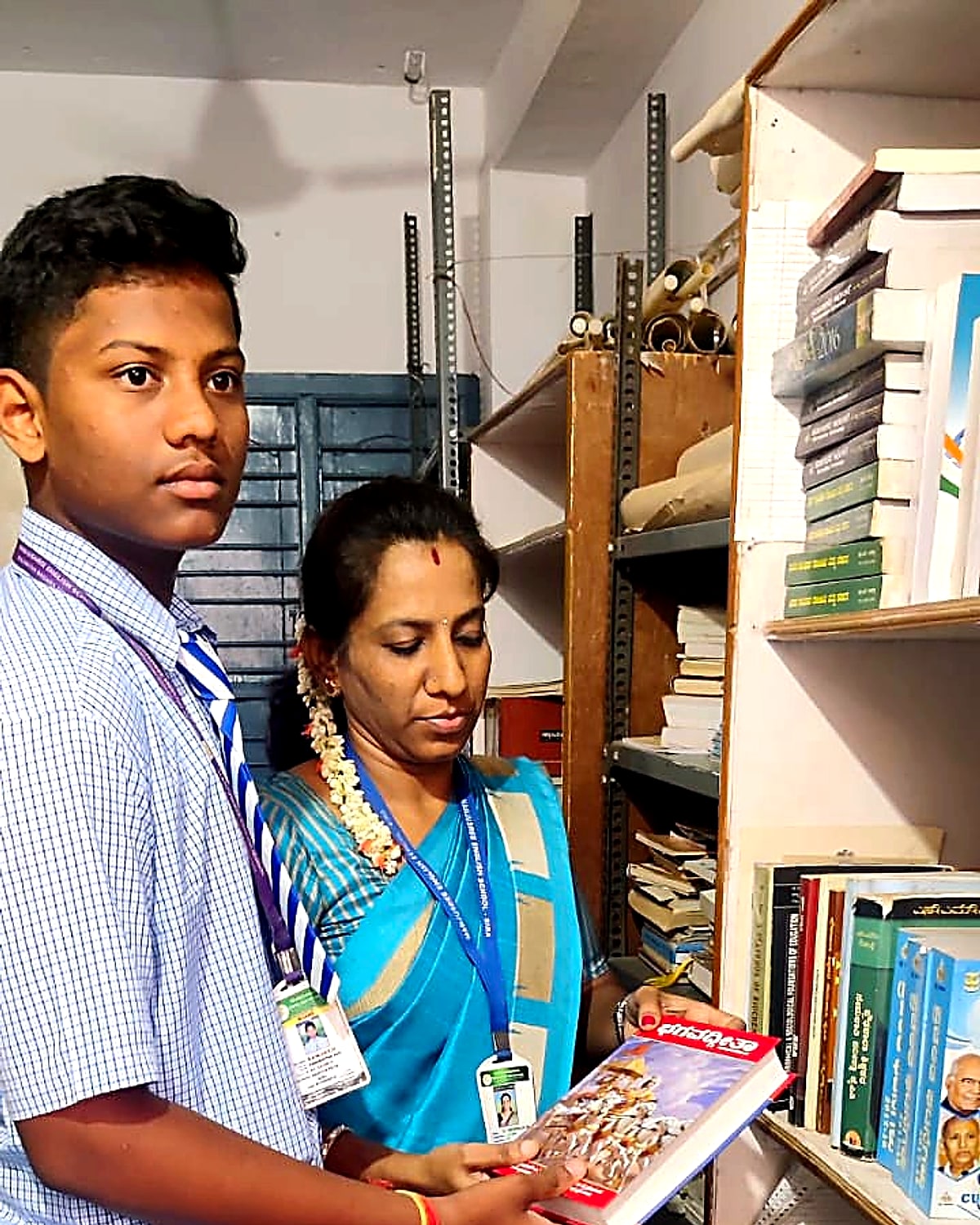 A Manjushree teacher helping a senior student select a book from the school library